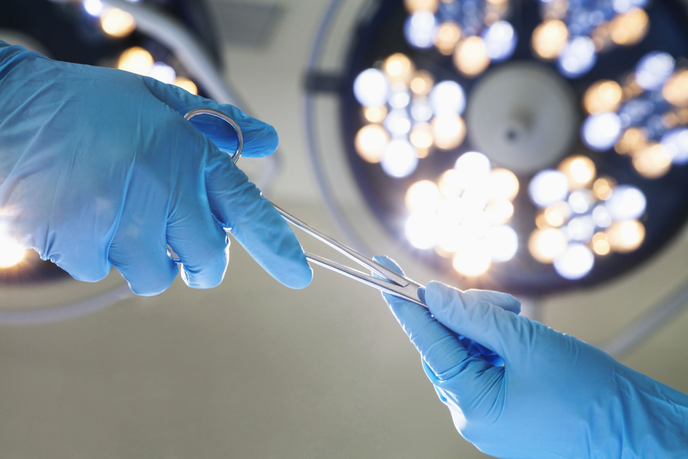 Surgeon passes forceps to assistant in an operating room, Cooley Dickinson Medical Group Plastic Surgery, Florence, MA 01062.
