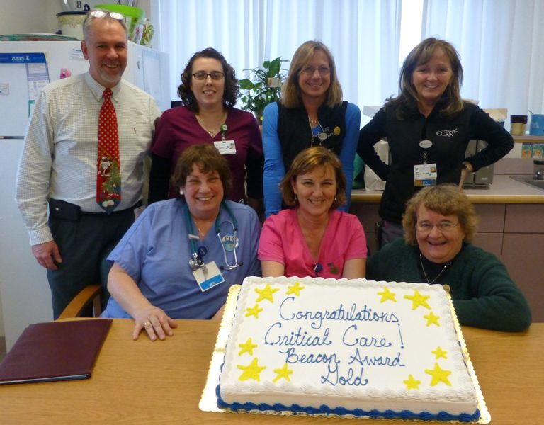 Members of the Cooley Dickinson Critical Care Team pose with a cake to celebrate the CCU’s accomplishment of earning a gold-level Beacon Award for Excellence in Patient Care.