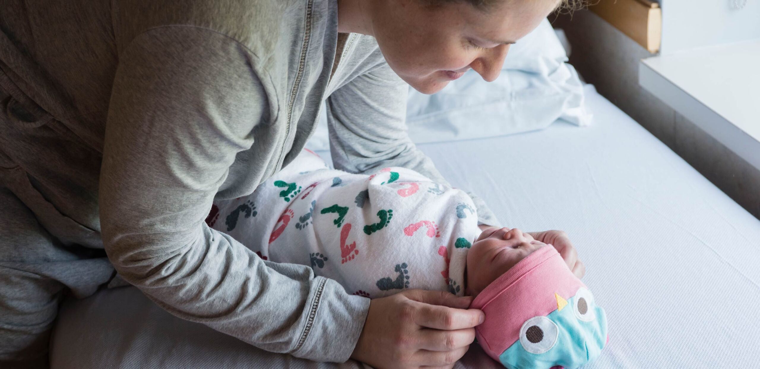 Mother leaning over newborn baby, smiling