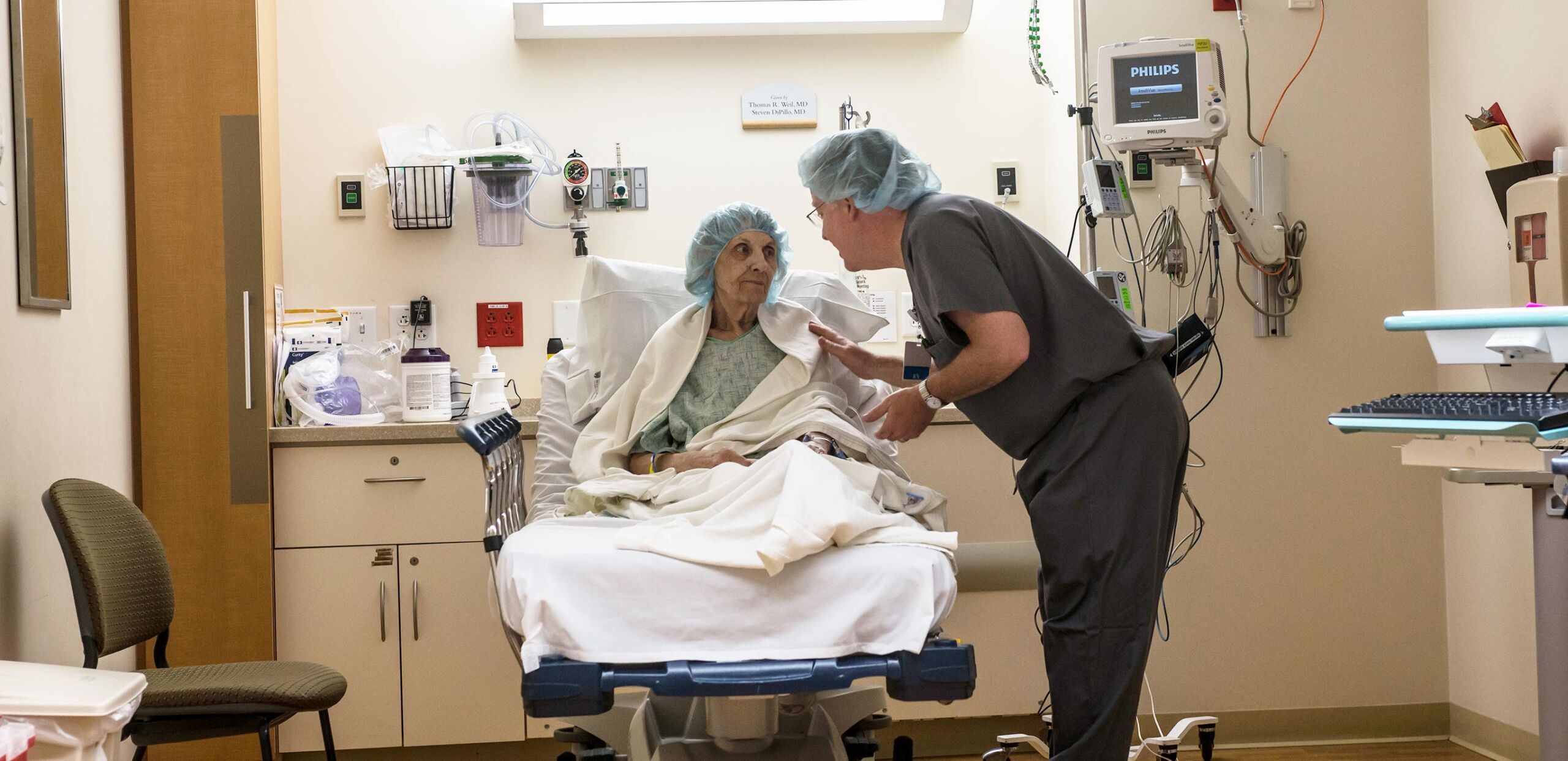 Male medical provider talks with elderly female cardiology patient in preparation for a procedure at Cooley Dickinson Hospital.