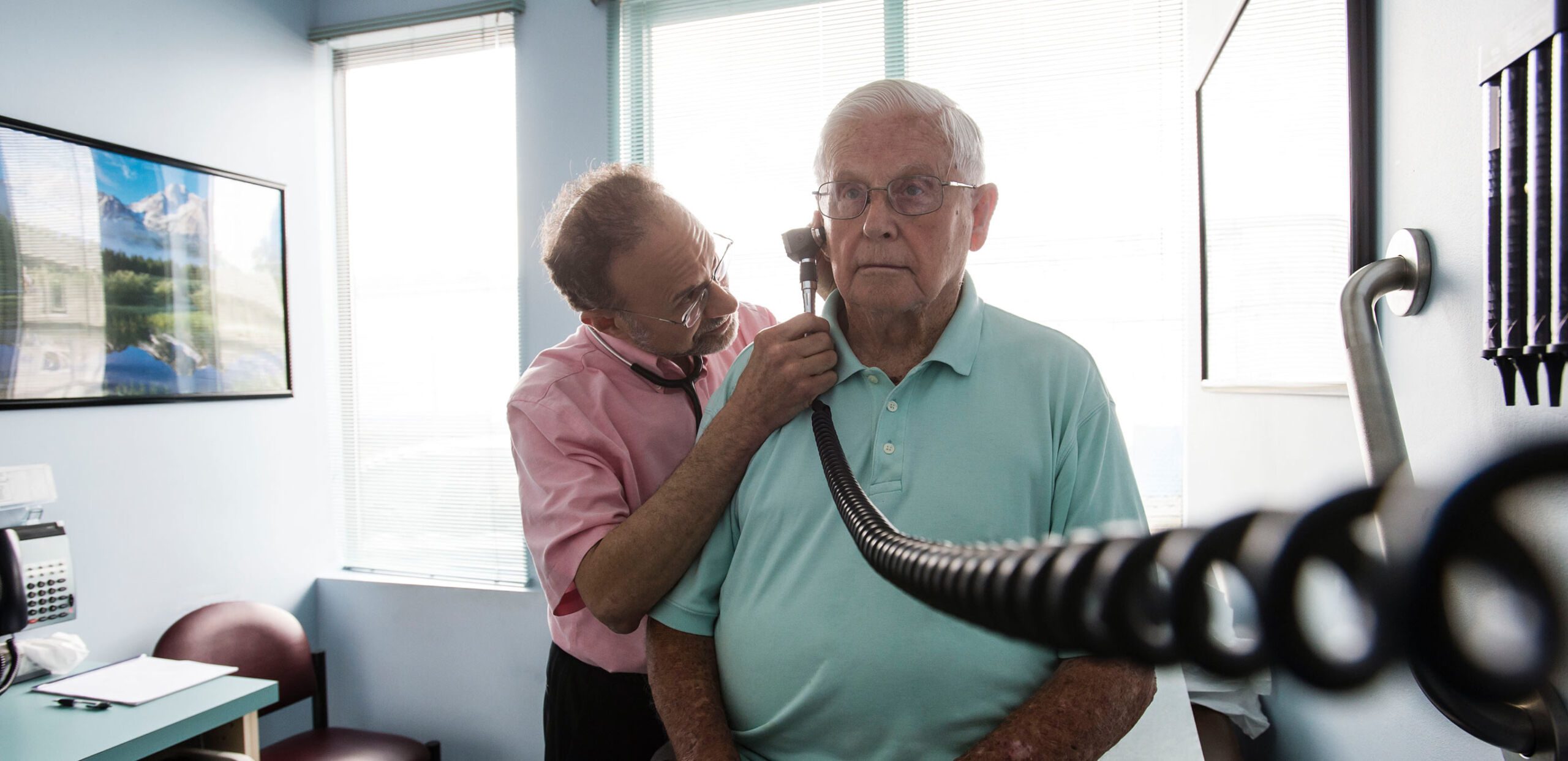 Internist David Alpern, MD. uses an otoscope to check the ear of a male patient at Conz Street Internal Medicine, Northampton, MA 01060.