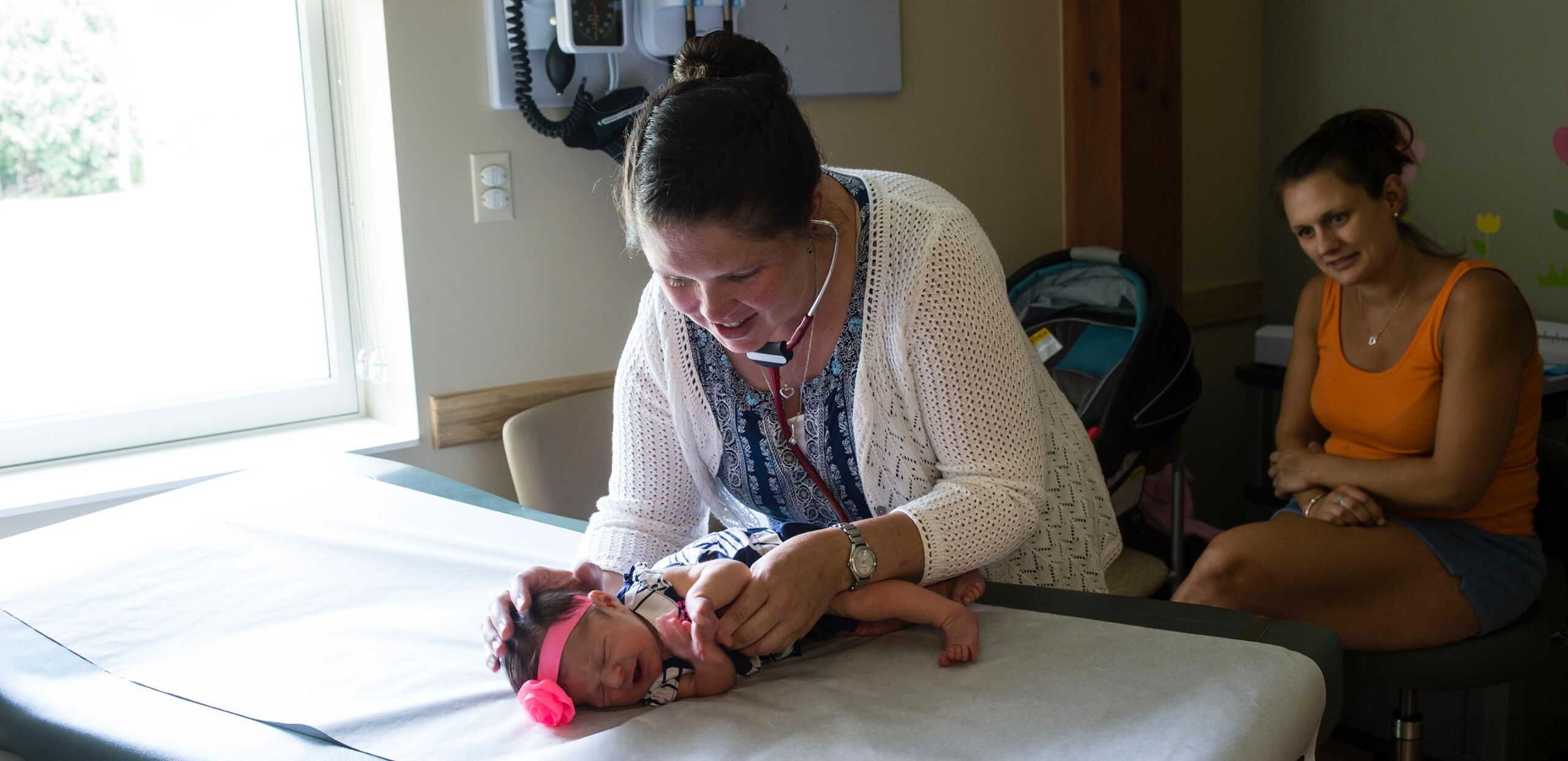 Pediatrician Jennifer Schott, MD, examines a newborn baby while mother watches at Sugarloaf Pediatrics, South Deerfield, MA 01373.