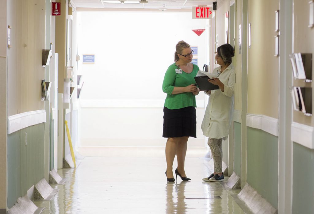 Two medical providers talking in hospital hallway