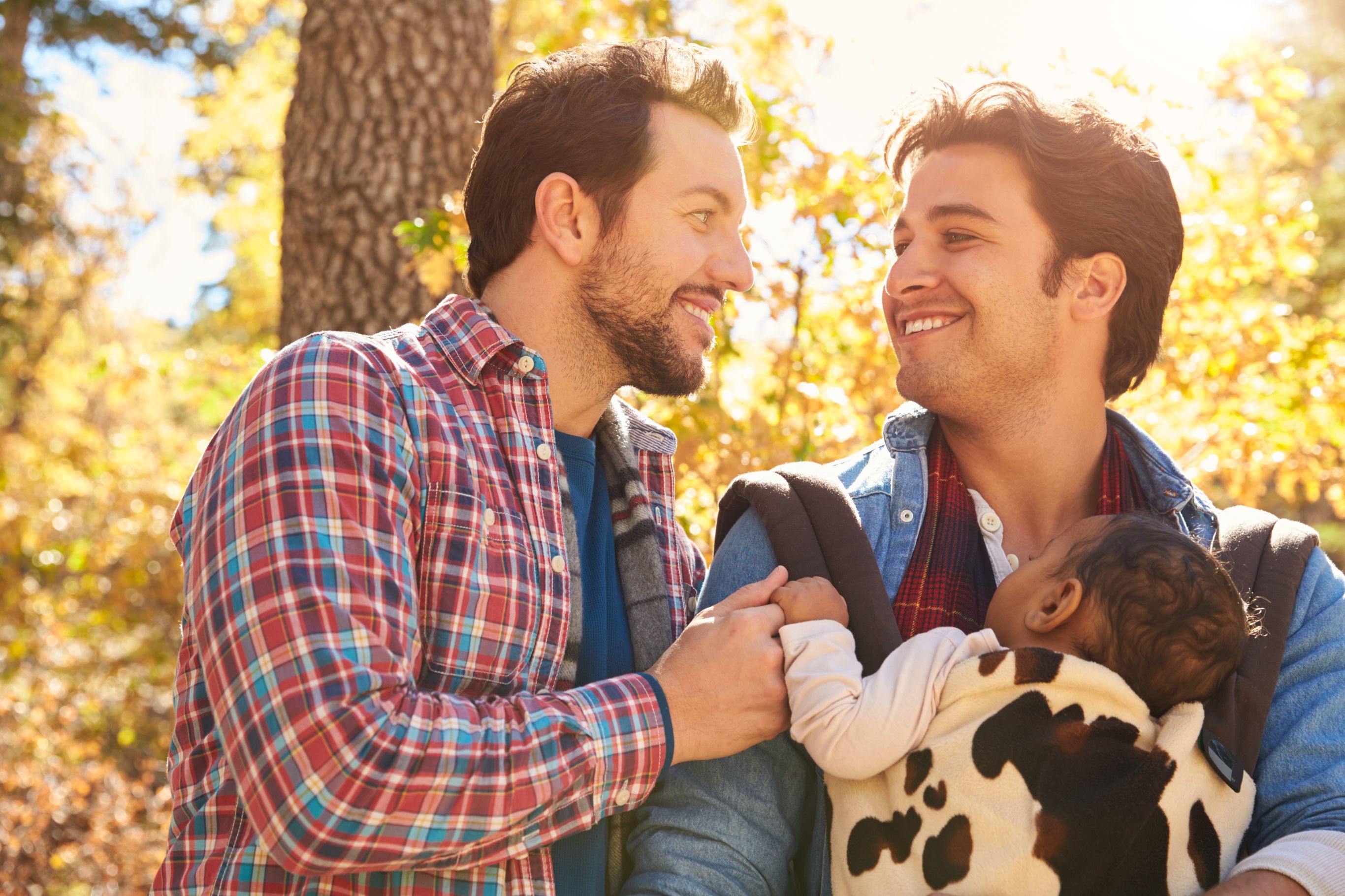 Male couple outside, smiling and holding a little girl