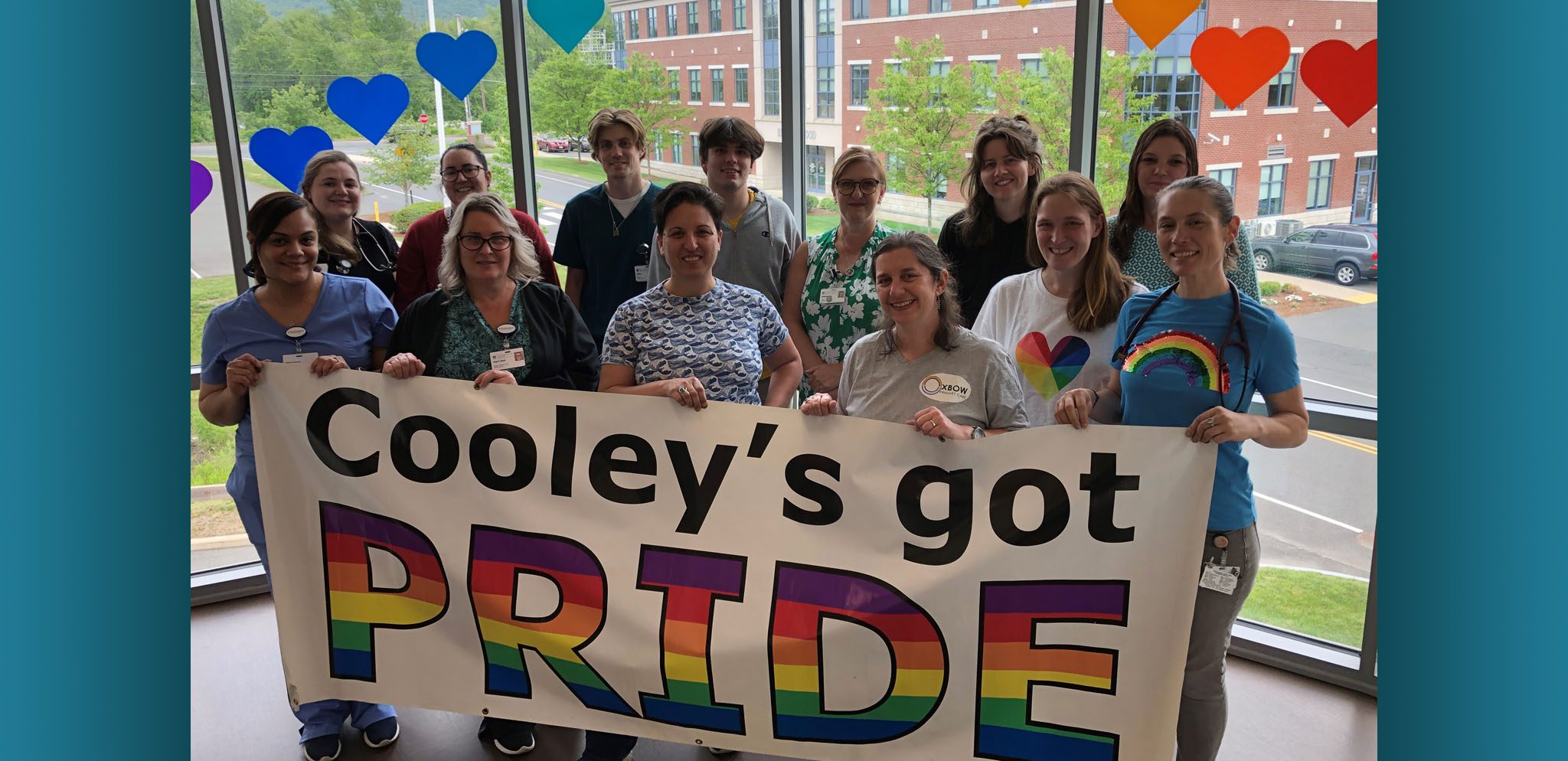 Oxbow staff members gathered together holding a "Cooley's Got Pride" sign