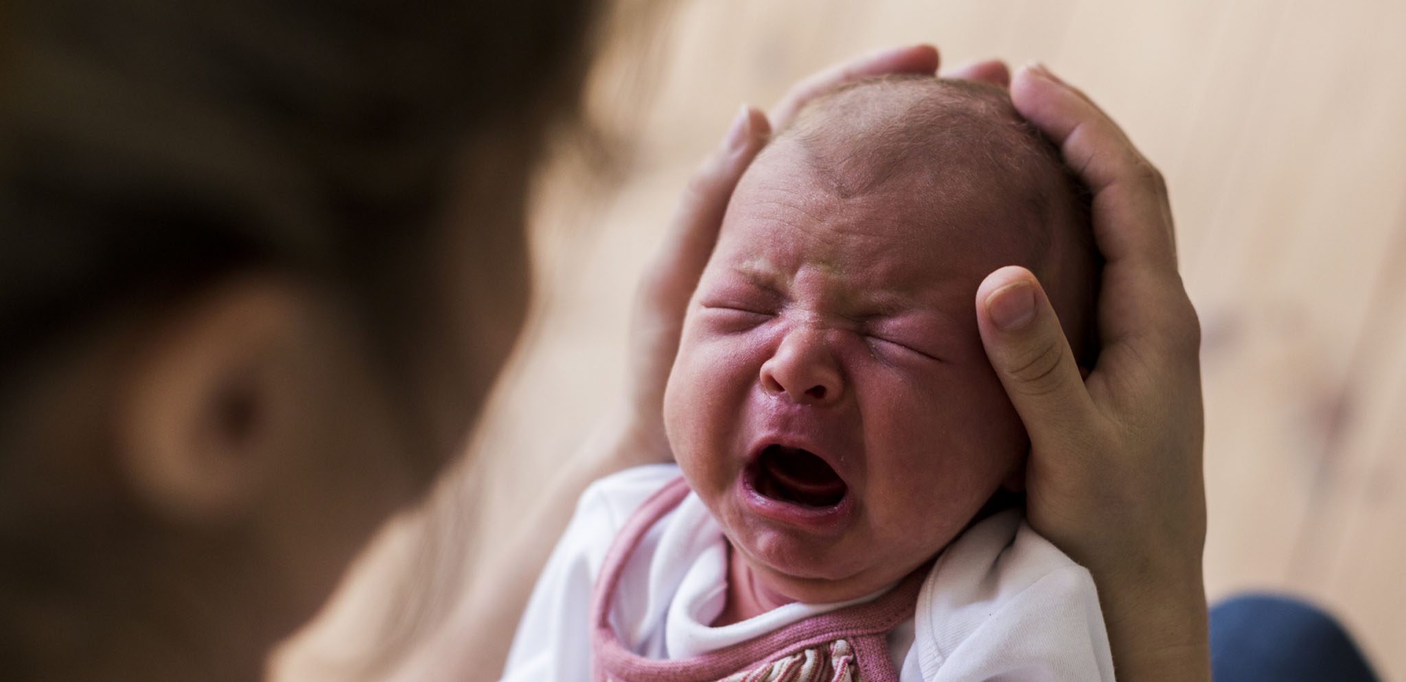 Newborn baby crying in parent's arms