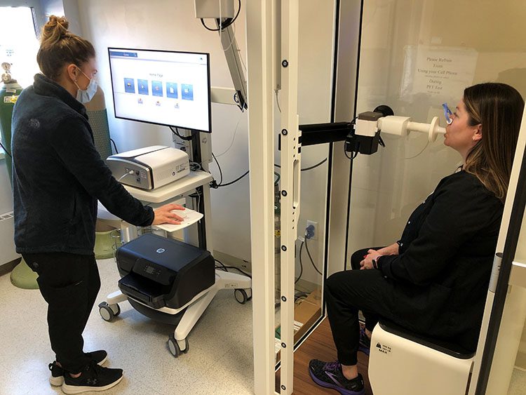 Respiratory Therapist Colleen Sarno demoing Cooley's new body plethysmography machine on a seated patient.