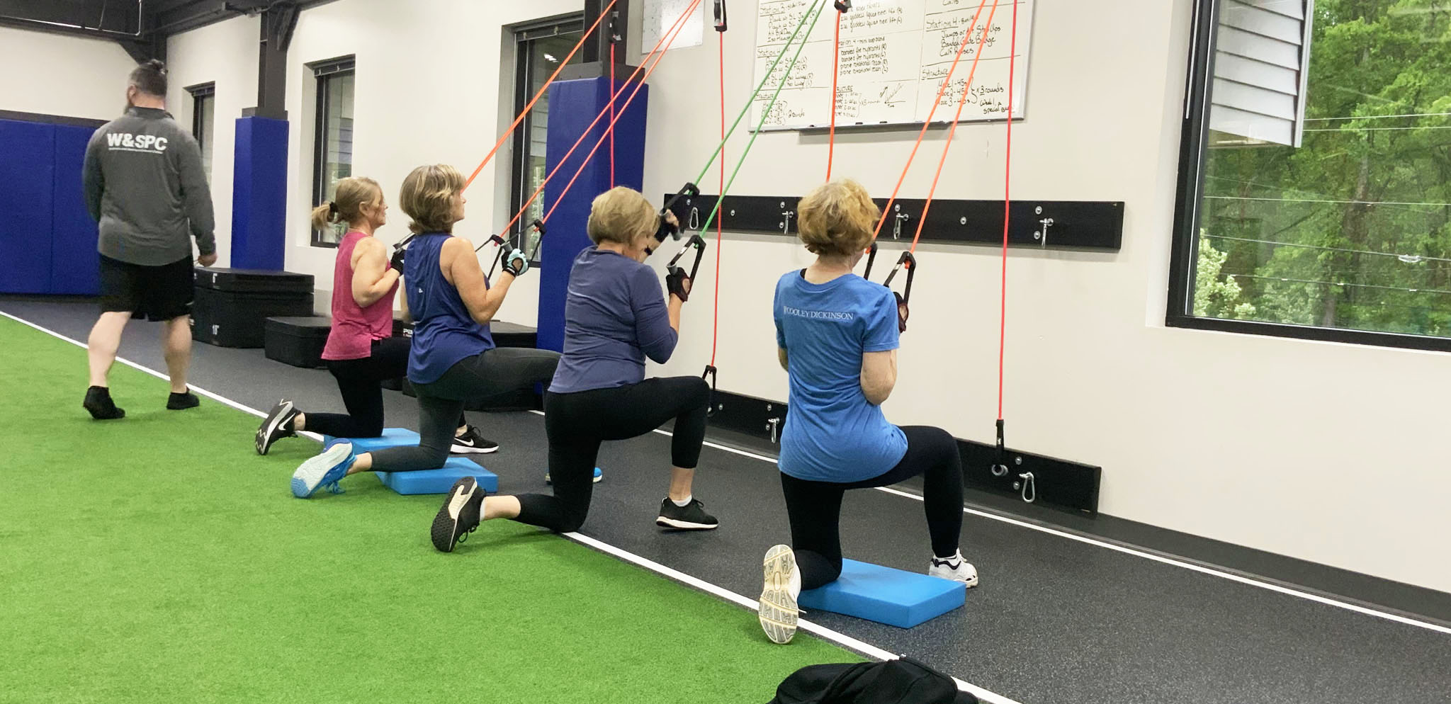 Four women working out in the wellness center while a staff member monitors