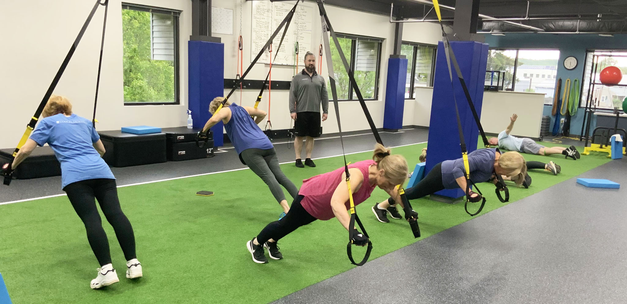 Several men and women working out in the wellness center while a staff member monitors