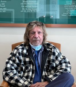 Man sitting in a hospital waiting room chair facing the camera