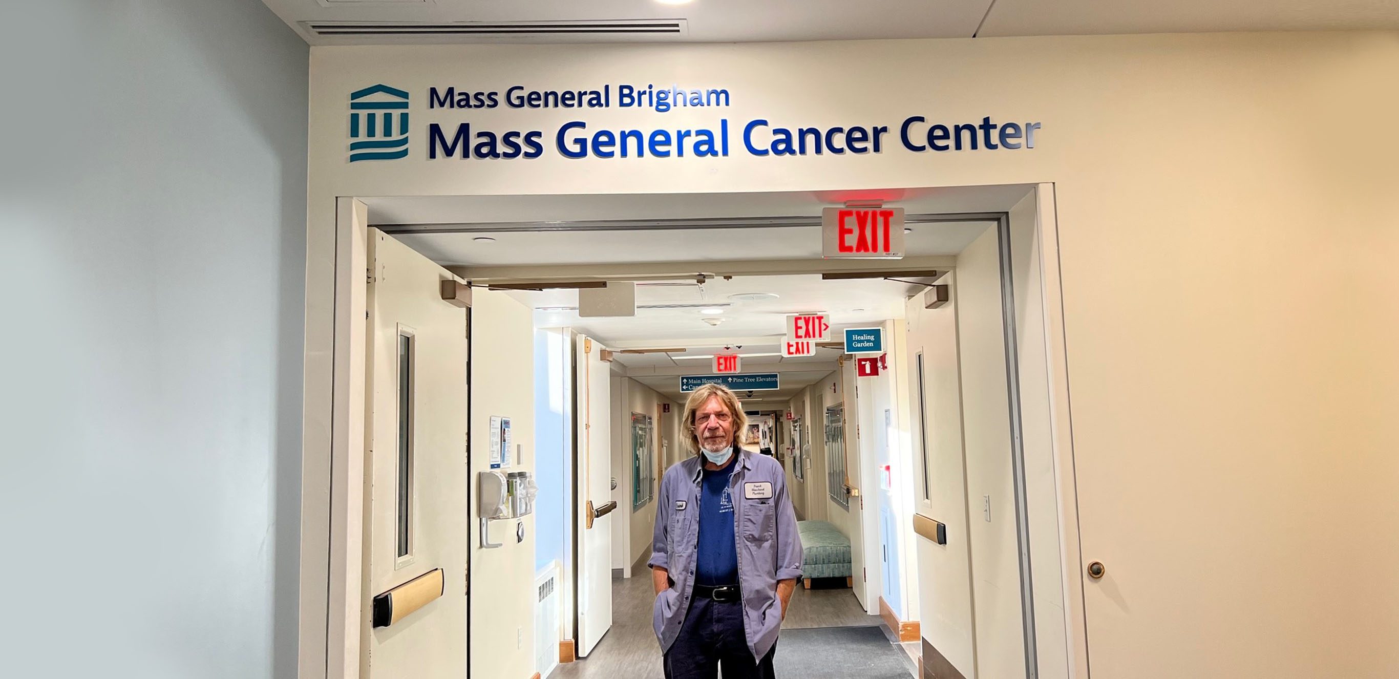 Man standing in hallway with Mass General Cancer Center written above the doorframe